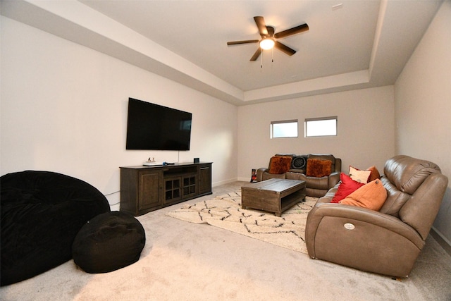 living room featuring light carpet, a tray ceiling, and ceiling fan