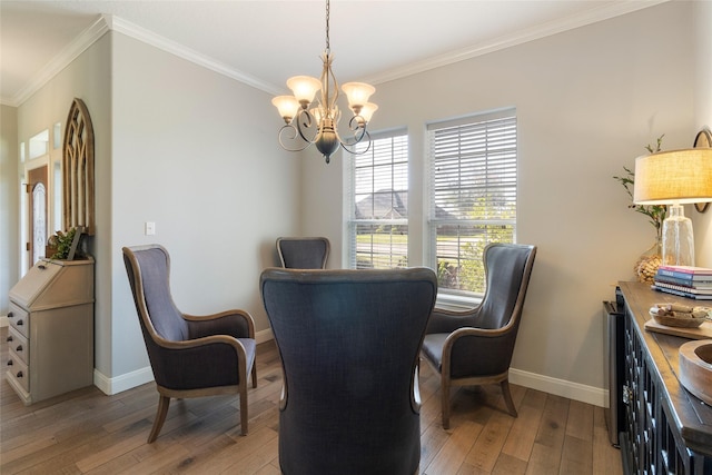 dining room featuring light wood-type flooring, ornamental molding, and an inviting chandelier