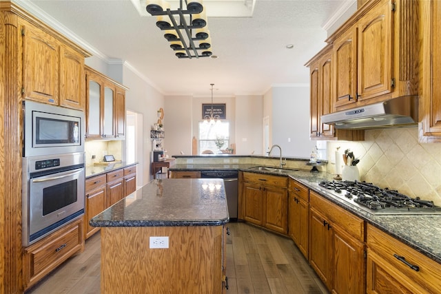 kitchen with sink, stainless steel appliances, kitchen peninsula, decorative light fixtures, and a kitchen island