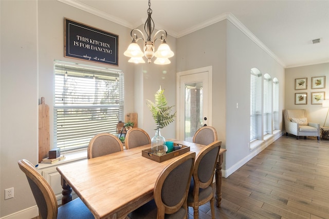 dining area featuring dark hardwood / wood-style floors, an inviting chandelier, and ornamental molding