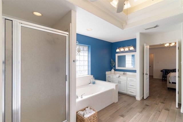 bathroom featuring hardwood / wood-style flooring, separate shower and tub, crown molding, and a tray ceiling