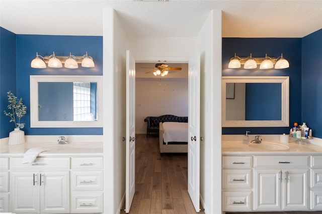 bathroom featuring ceiling fan, vanity, wood-type flooring, and a textured ceiling