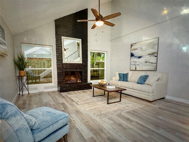 living room with hardwood / wood-style floors, ceiling fan, high vaulted ceiling, and a brick fireplace