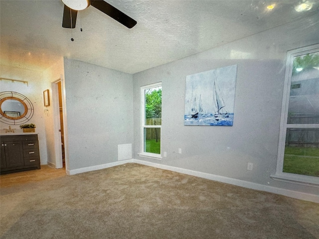 unfurnished bedroom featuring ceiling fan, sink, ensuite bathroom, and light carpet