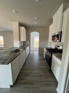 kitchen with a wealth of natural light, white cabinetry, stainless steel appliances, and dark hardwood / wood-style floors