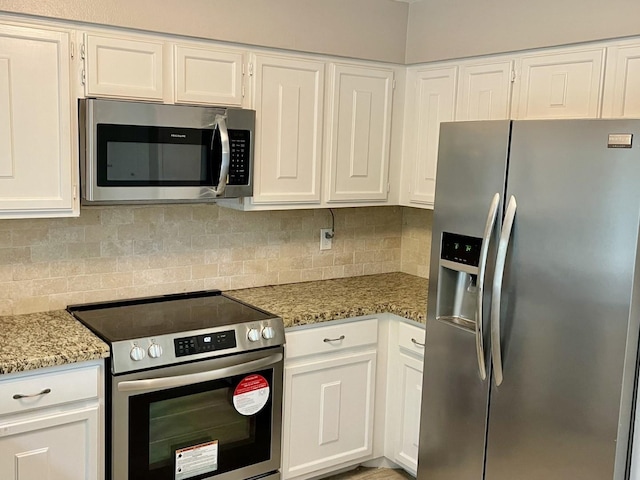 kitchen with light stone countertops, appliances with stainless steel finishes, backsplash, and white cabinetry