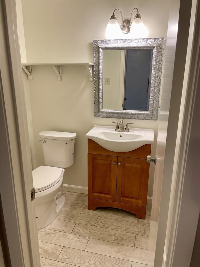 bathroom with wood-type flooring, vanity, and toilet