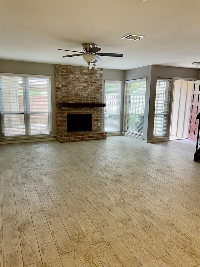 unfurnished living room featuring a wealth of natural light, a fireplace, and light hardwood / wood-style floors