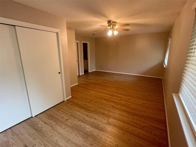 unfurnished bedroom featuring hardwood / wood-style floors, ceiling fan, and a closet