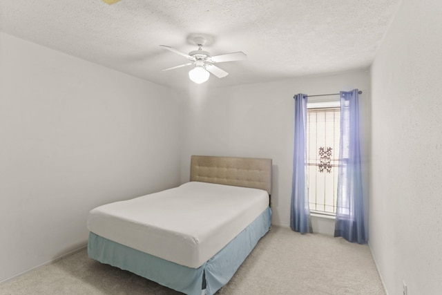 carpeted bedroom featuring ceiling fan and a textured ceiling