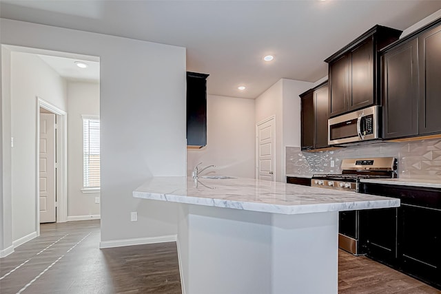 kitchen with hardwood / wood-style floors, sink, tasteful backsplash, kitchen peninsula, and stainless steel appliances