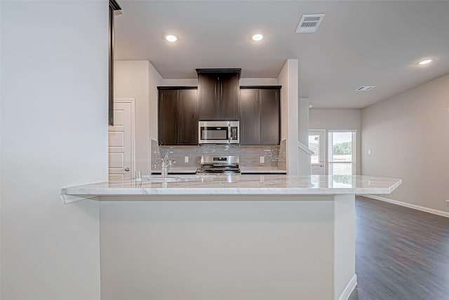 kitchen with backsplash, sink, dark hardwood / wood-style flooring, dark brown cabinetry, and stainless steel appliances