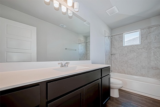 full bathroom with vanity, tiled shower / bath combo, hardwood / wood-style flooring, and toilet