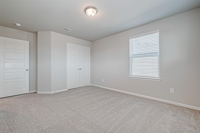 unfurnished bedroom with light colored carpet and a closet