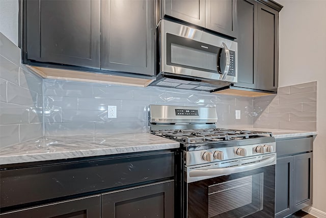 kitchen with backsplash, gray cabinets, light stone counters, and appliances with stainless steel finishes