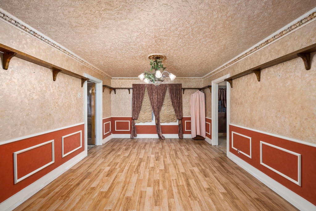 interior space featuring hardwood / wood-style floors, ornamental molding, and an inviting chandelier