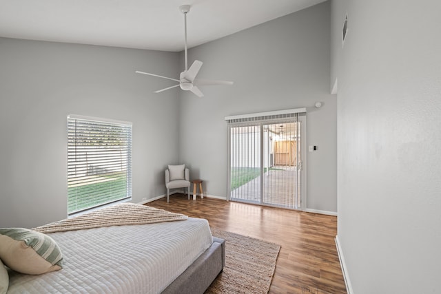 bedroom featuring access to exterior, ceiling fan, hardwood / wood-style floors, and high vaulted ceiling