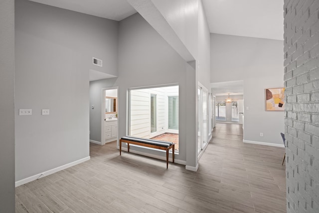 hallway with light hardwood / wood-style floors and high vaulted ceiling