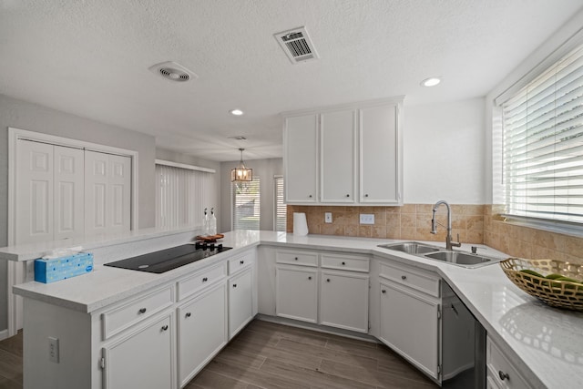 kitchen featuring kitchen peninsula, black electric cooktop, white cabinets, and sink