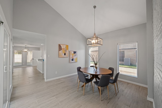 dining area featuring light hardwood / wood-style floors, high vaulted ceiling, and an inviting chandelier