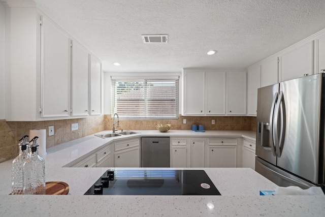 kitchen with decorative backsplash, a textured ceiling, stainless steel appliances, sink, and white cabinets