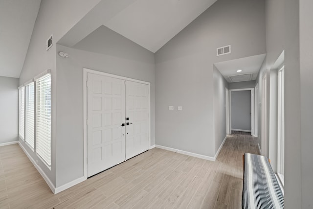 foyer entrance with light hardwood / wood-style flooring and high vaulted ceiling