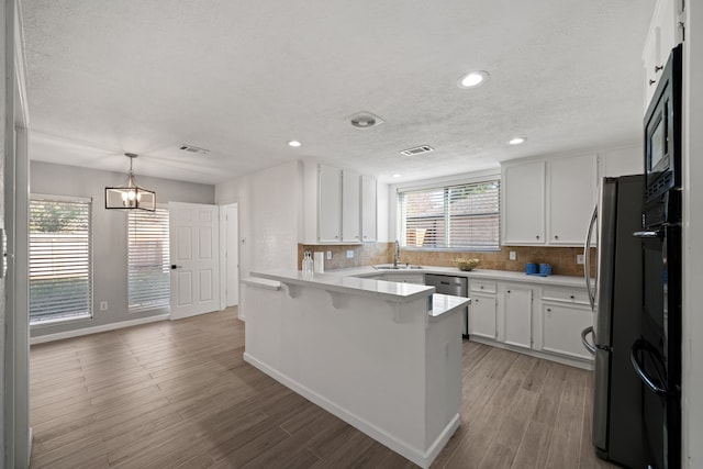 kitchen with hardwood / wood-style floors, plenty of natural light, white cabinetry, and kitchen peninsula