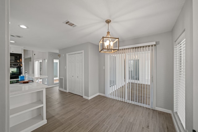 unfurnished dining area with a chandelier and wood-type flooring