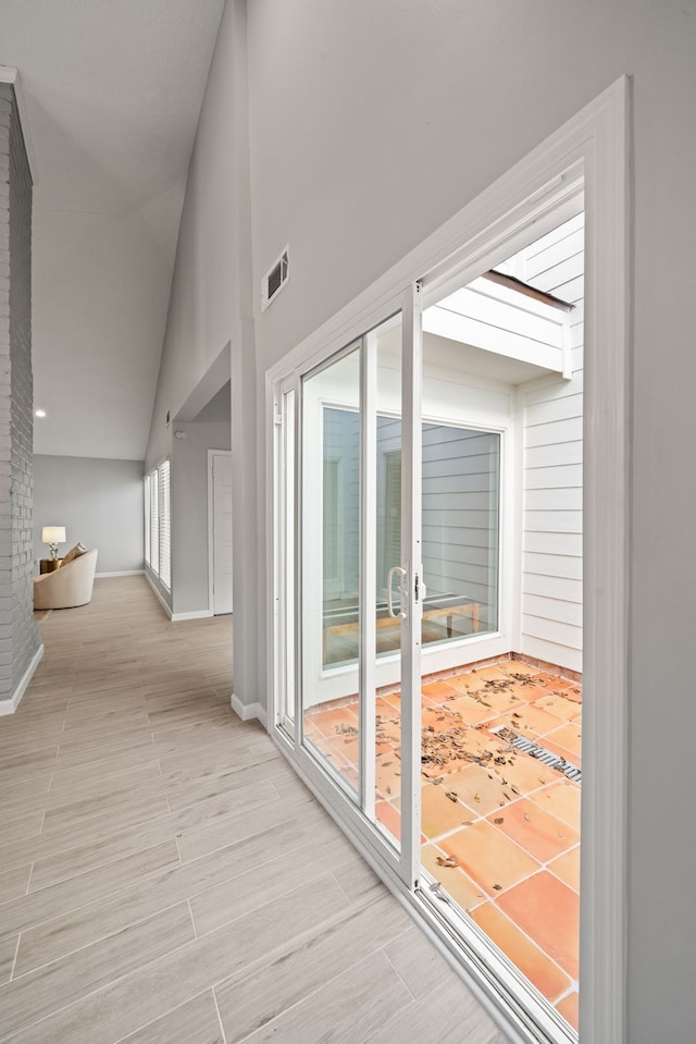 hall featuring high vaulted ceiling and light hardwood / wood-style floors