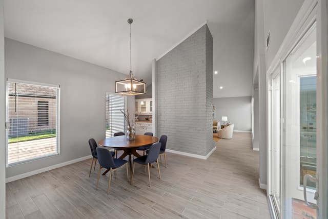 dining space with a notable chandelier, light hardwood / wood-style floors, and lofted ceiling