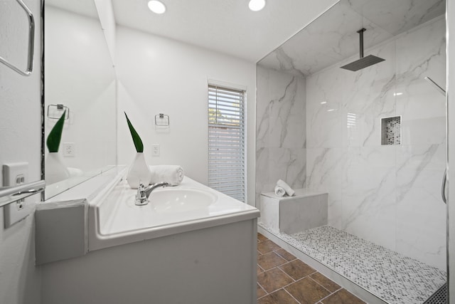 bathroom with tile patterned flooring, vanity, and tiled shower