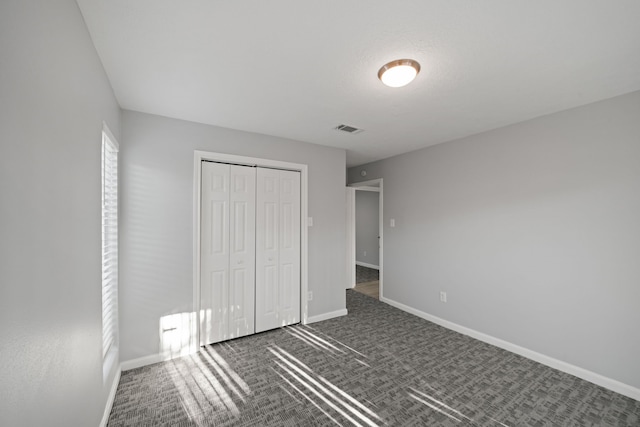 unfurnished bedroom with dark colored carpet and a closet