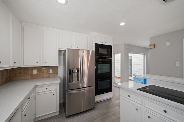 kitchen featuring backsplash, black appliances, hardwood / wood-style flooring, a textured ceiling, and white cabinetry