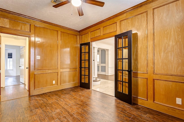 unfurnished room featuring a textured ceiling, dark wood-type flooring, french doors, ornamental molding, and ceiling fan