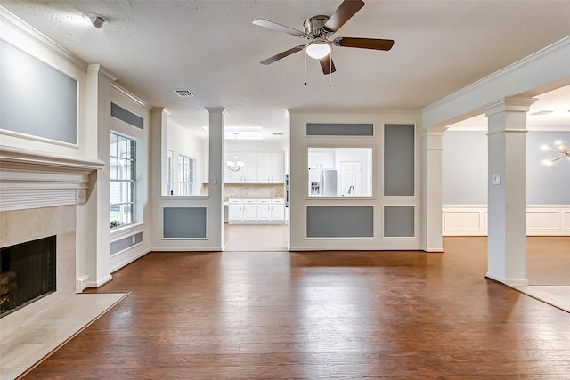 unfurnished living room with ceiling fan with notable chandelier, hardwood / wood-style floors, a high end fireplace, and crown molding