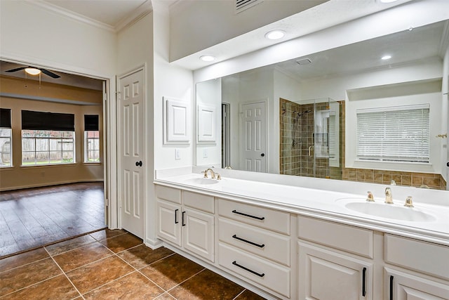 bathroom with crown molding, tile patterned flooring, ceiling fan, tiled shower, and vanity