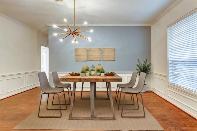 dining room featuring crown molding, hardwood / wood-style flooring, and an inviting chandelier