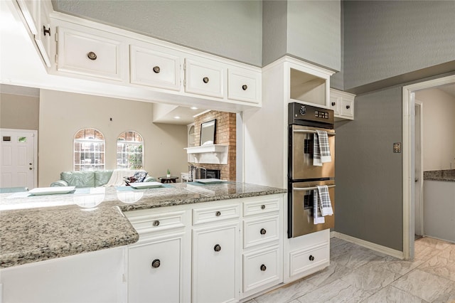 kitchen featuring light stone counters, white cabinetry, and double wall oven