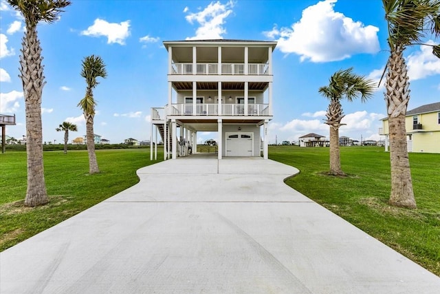 coastal inspired home with a balcony, a carport, a front yard, a garage, and covered porch