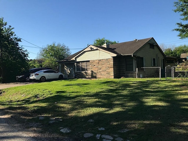 view of side of property featuring stone siding, fence, and a lawn