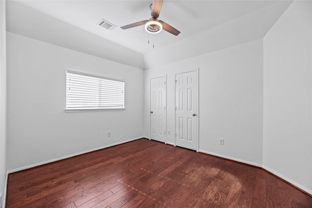 unfurnished bedroom featuring multiple closets, lofted ceiling, dark wood-type flooring, and ceiling fan