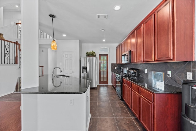 kitchen featuring appliances with stainless steel finishes, pendant lighting, sink, dark stone countertops, and decorative backsplash