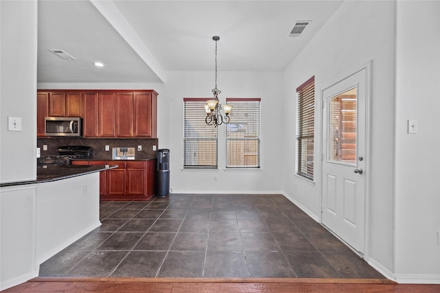 kitchen with range, a chandelier, decorative light fixtures, dark tile patterned floors, and backsplash