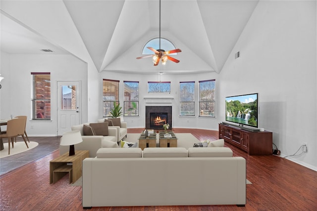 living room featuring high vaulted ceiling, dark wood-type flooring, a tile fireplace, and ceiling fan