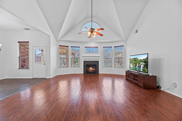 unfurnished living room with dark wood-type flooring, ceiling fan, high vaulted ceiling, and a tile fireplace