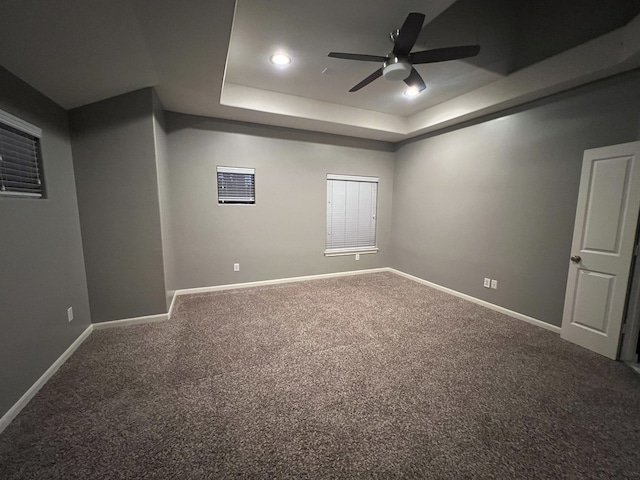 empty room with carpet flooring, ceiling fan, and a tray ceiling