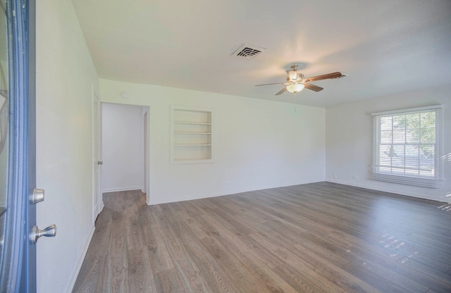 empty room featuring ceiling fan, built in features, and hardwood / wood-style flooring