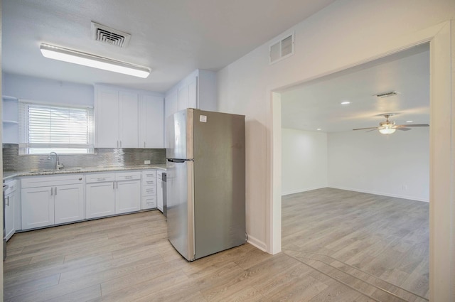 kitchen with stainless steel refrigerator, white cabinetry, sink, ceiling fan, and light wood-type flooring