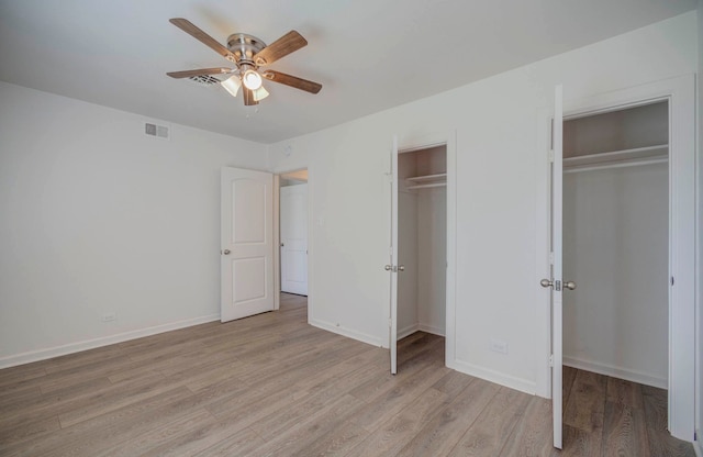 unfurnished bedroom featuring light wood-type flooring, two closets, and ceiling fan