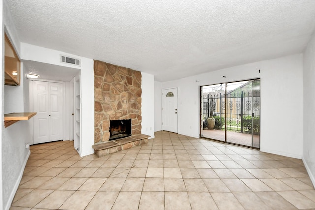 unfurnished living room featuring a fireplace, a textured ceiling, and light tile patterned flooring